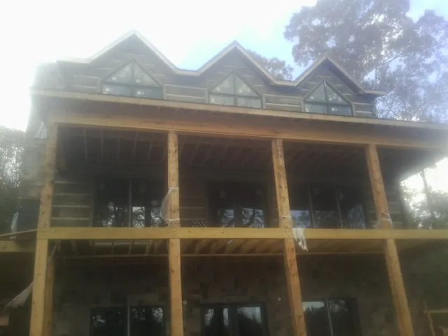 Dormers and porch framing on a large log home under construction — Roof Coating work by our crew in Goldsboro