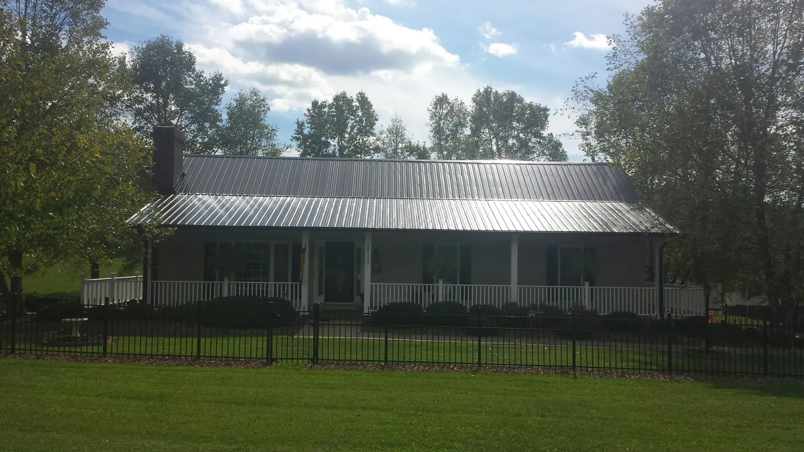Gray metal roof on a brick ranch with a full width front porch — Gutter Guard Installation work by our crew in Goldsboro