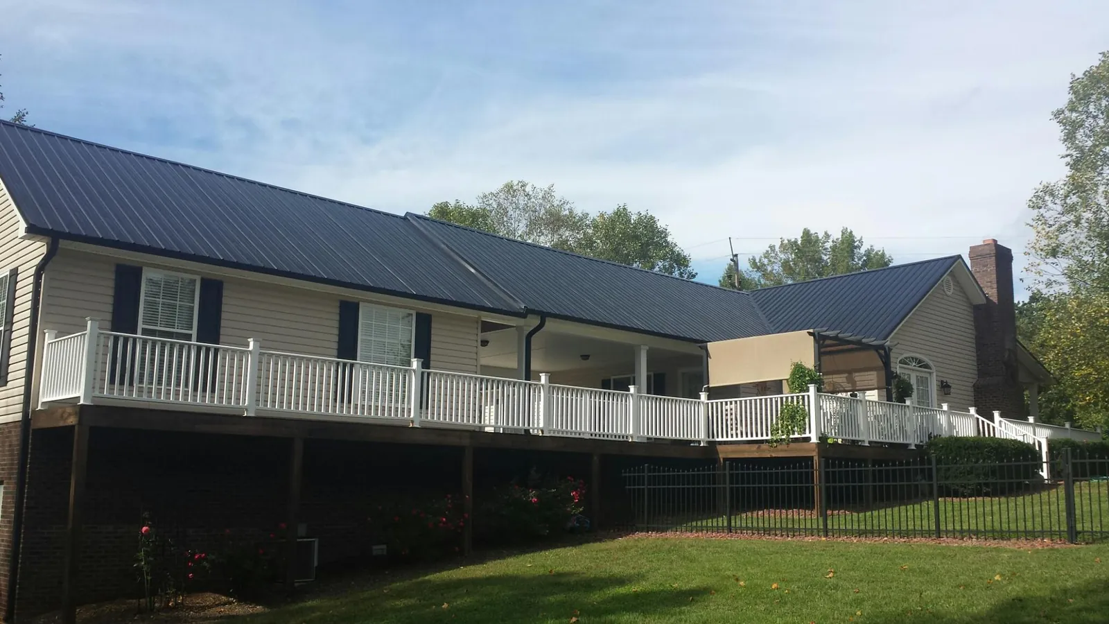 Black metal roof above a long white railed deck on a hillside home in Goldsboro
