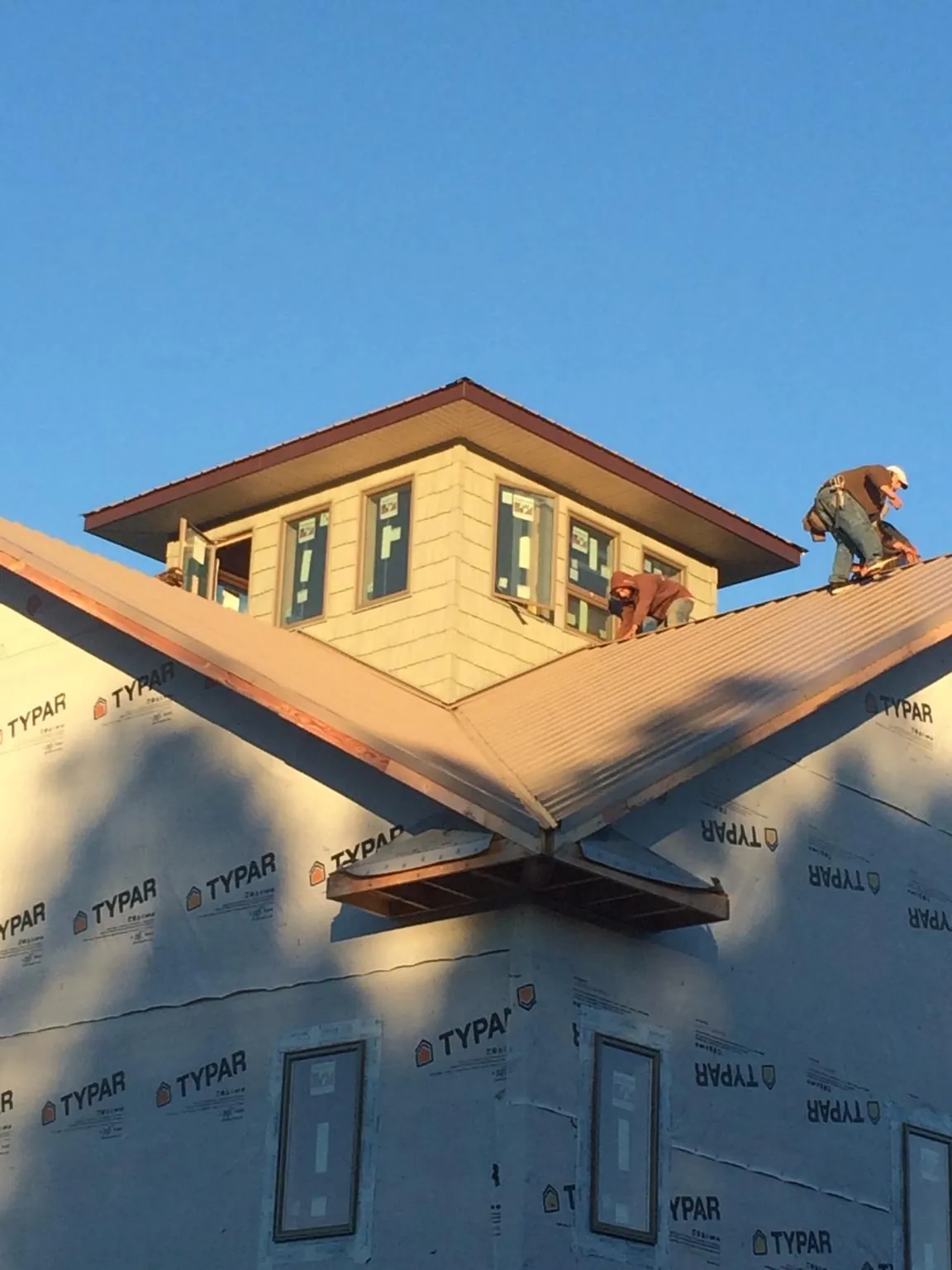 Roofers working around a rooftop cupola on a new metal roof at sunset — Roof Waterproofing in Goldsboro by Roofing Brothers
